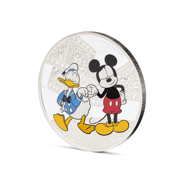 Add some bromance with this adorable 3oz pure silver coin for Disney’s Mickey Mouse and Donald Duck! Shows the two beloved best friends in colour, wearing their classic get-up and sharing a fist bump, which stands out against the mirrored background. - New Zealand Mint
